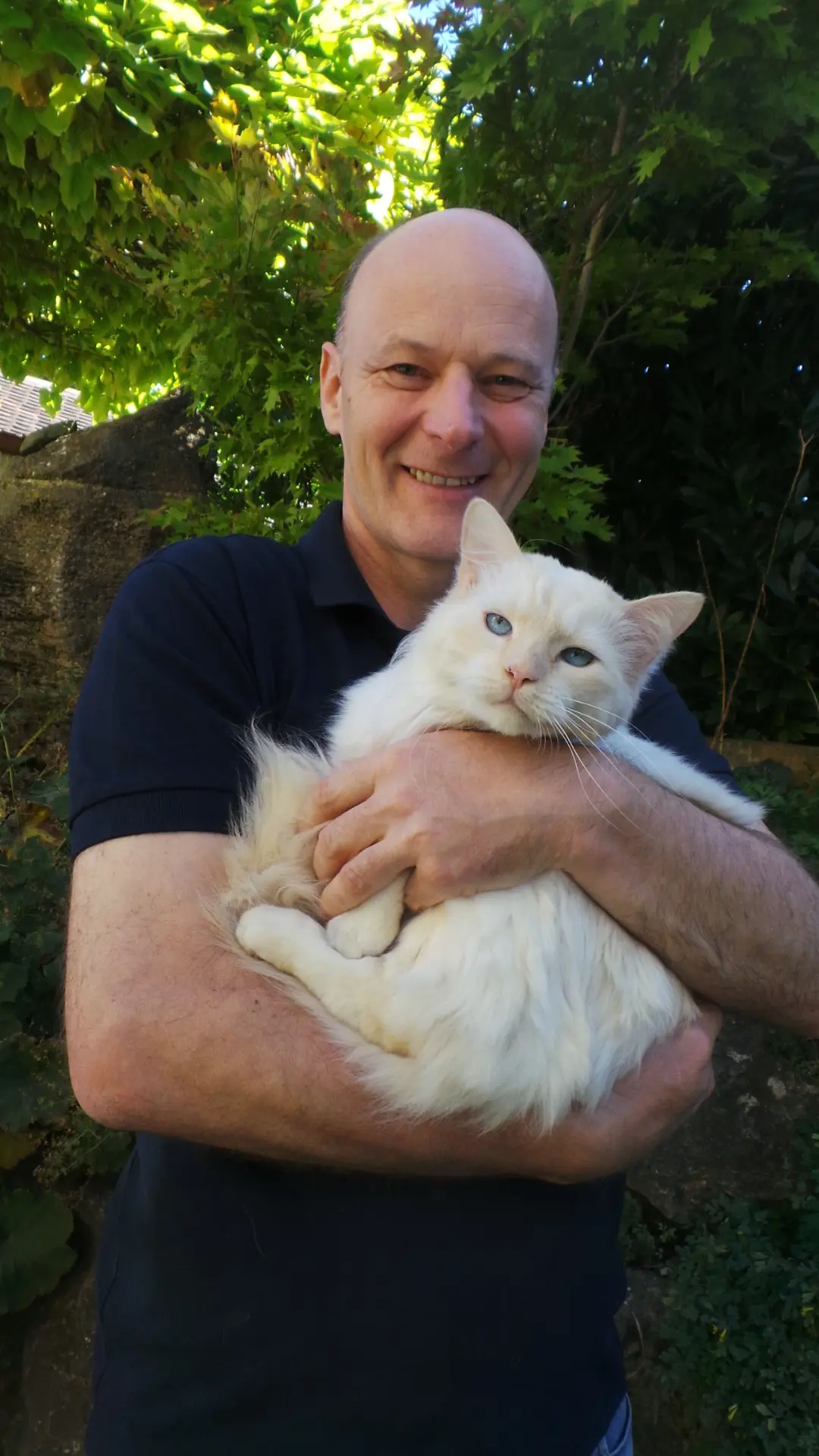 Christoph Schäuble mit einer weißen Katze auf dem Arm